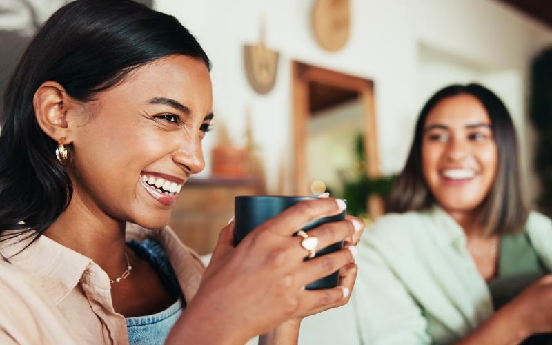 two women smiling and holding drinks