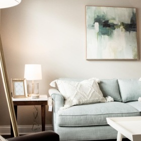 a living room with a couch, tables and a lamp