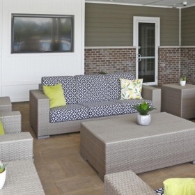 a patio with a tv, table, chairs and couches
